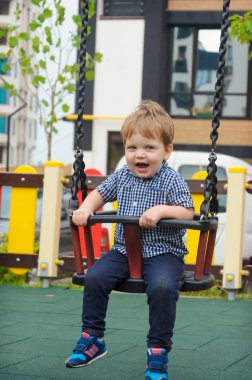 Yayınlanan ekose gömlek, kot pantolon ve spor ayakkabı rides neşeli küçük çocuk bir