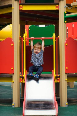 Küçük çocuk bir ekose gömlek, kot pantolon ve spor ayakkabı içinde bir childre sürmek