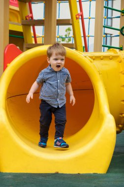 Küçük çocuk bir ekose gömlek, kot pantolon ve spor ayakkabı içinde bir childre sürmek