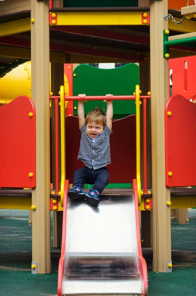 Küçük çocuk bir ekose gömlek, kot pantolon ve spor ayakkabı içinde bir childre sürmek