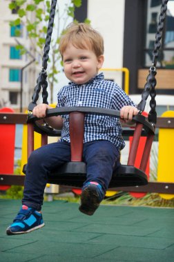 Yayınlanan ekose gömlek, kot pantolon ve spor ayakkabı rides neşeli küçük çocuk bir