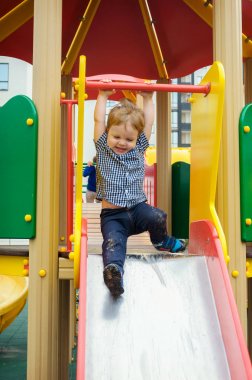 Küçük çocuk bir ekose gömlek, kot pantolon ve spor ayakkabı içinde bir childre sürmek