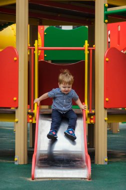 Küçük çocuk bir ekose gömlek, kot pantolon ve spor ayakkabı içinde bir childre sürmek