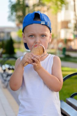 Mavi şapka ve beyaz t-shirt bir buz cre yeme düşünceli çocuk