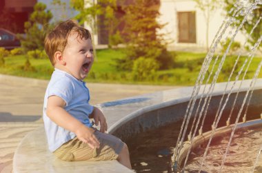 Şort ve tişört vesilesi kenarında oturan küçük çocuk