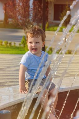 Şort ve tişört vesilesi kenarında oturan küçük çocuk