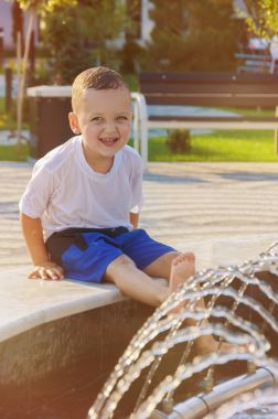 Şort ve tişört vesilesi kenarında oturan küçük çocuk