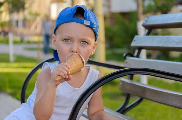 Ragazzino pensieroso mangia un cono gelato su una panchina — Foto Stock