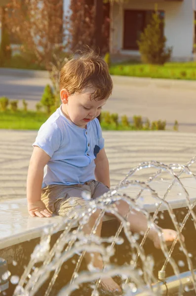 Şort ve tişört vesilesi kenarında oturan küçük çocuk