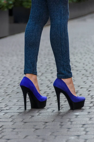 Hermosas piernas delgadas femeninas en jeans ajustados y zapatos azules en un —  Fotos de Stock