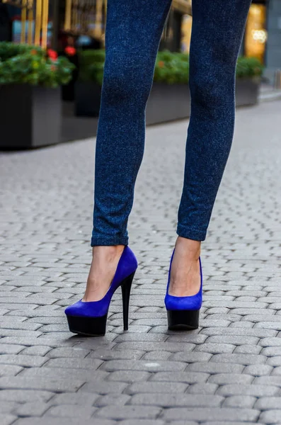 Belles jambes féminines minces en jeans serrés et chaussures bleues sur un — Photo