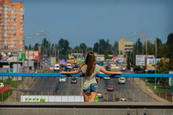Hermosa chica elegante estudiante se para en el puente del coche con una b — Foto de Stock