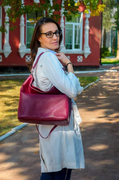 Mulher elegante magro em um manto branco com um saco de borgonha — Fotografia de Stock