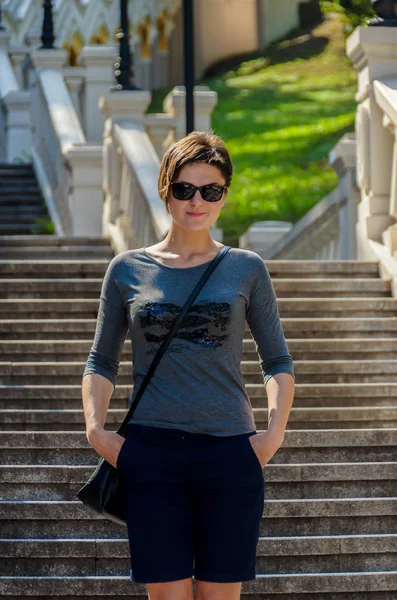 Hermosa mujer morena delgada con un peinado corto, gafas de sol — Foto de Stock