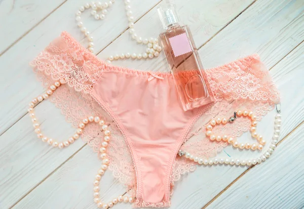 Jemné růžové krajkové kalhotky, parfémy a perle — Stock fotografie