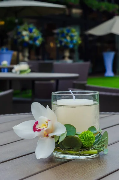 Arranjo de flor bonito com uma orquídea e velas em um gla — Fotografia de Stock