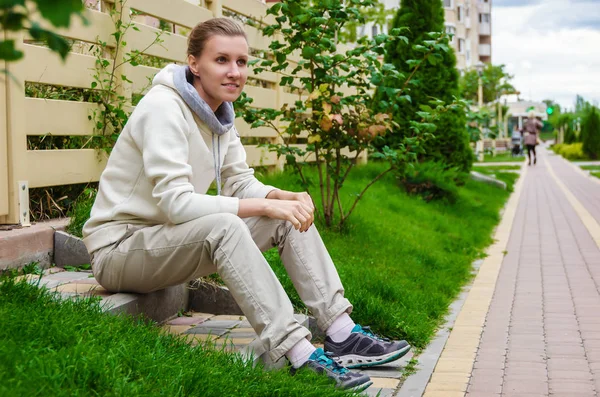 Slanke vrouw in een beige sport pak zit op de trappen van haar po — Stockfoto