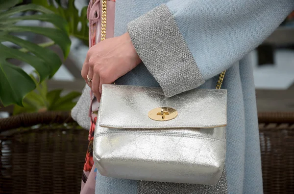 elegant small silver leather bag in the hands of a fashionista.