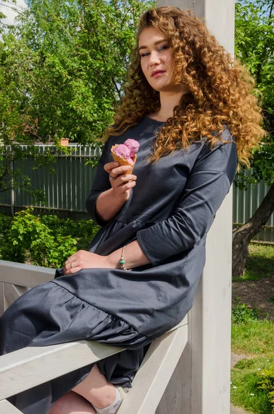 Stilvolle Frau mit schickem lockigem Haar, die im Hof Eis isst — Stockfoto