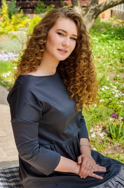 Lovely woman with chic curly hair resting in the backyard of his — Stock Photo, Image