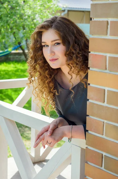 Mooie vrouw met chique krullend haar, leunend op de balustrade en loo — Stockfoto