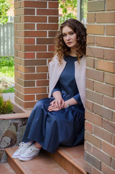 Mulher agradável com cabelo encaracolado chique em um vestido cinza longo e uma luz — Fotografia de Stock