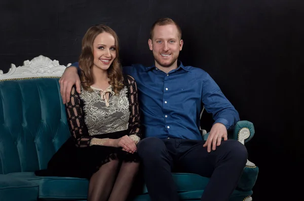 Bella innamorata giovane coppia in abiti classici si siede su un blu — Foto Stock