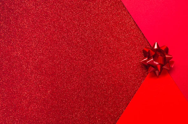 Três tons de vermelho com brilhos de férias e um presente de arco — Fotografia de Stock