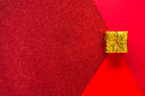 A piros három árnyalata az ünnepi csillogással és egy arany ajándékdobozzal. — Stock Fotó