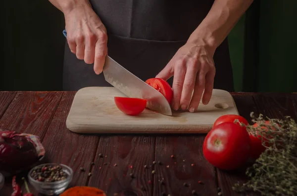 Vackra kvinnliga händer skär färsk tomat på en träskiva. Vegetabiliskt — Stockfoto