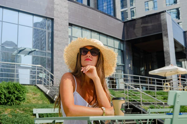 Mooie slanke gebruinde vrouw in een strohoed en een witte sundre — Stockfoto