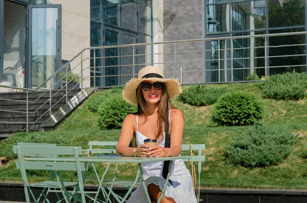 Mooie slanke gebruinde vrouw in een strohoed en een witte sundre — Stockfoto