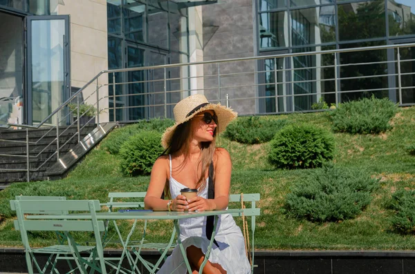 Mooie slanke gebruinde vrouw in een strohoed en een witte sundre — Stockfoto