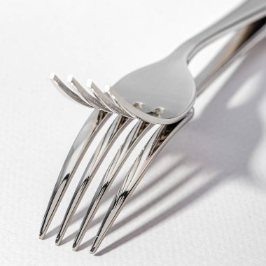 Hafif arka planda iki metal parlak çatal. 