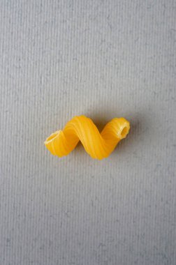 Gri arka planda tek makarna spiralleri (Cavatappi). İtalyan ulusal mutfağı - çiğ makarna