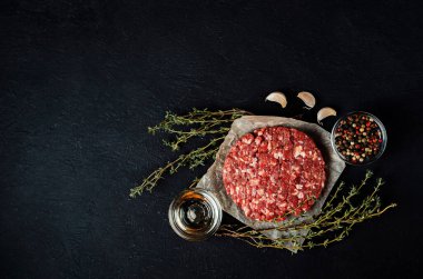 Siyah arka planda baharatlı köfteler için taze çiğ et. Parşömen kağıdında çiğ pirzola. Billetler, yarı bitmiş ürünler. Et yemekleri hazırlamak için gerekli malzemeler.