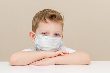 Tıbbi maske takan dört yaşında tatlı bir çocuk. Salgın yüzünden karantinaya alınmış çocuklar. Çocuk evde üzgün ve yalnız oturuyor.