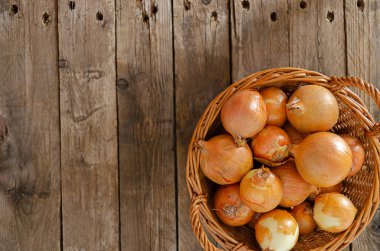 Eski ahşap bir masada soğanlı hasır sepet. Kırsal yaşam