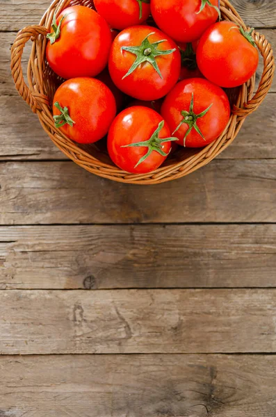 古い木製のテーブルの上にトマトとウィッカーバスケット 田舎の静物 — ストック写真