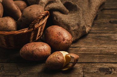 Tahta bir masada patates dolu sepet. Kırsal yaşam, patates soymak. Sıradan, sıradan, geleneksel yemekler..