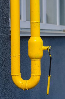 Çok katlı bir binanın ön cephesinde havalandırması olan sarı gaz borusu. Ev içi kullanım için doğal gaz, gaz boru hattı. Konut binalarının gazlaştırılması