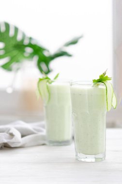 Salatalık ve bitkilerle mayalanmış süt içeceği. Işıl ışıl bir masada böyle bir kokteyl içen iki kişi. Sıcak bir yaz için ferahlatıcı bir içecek.