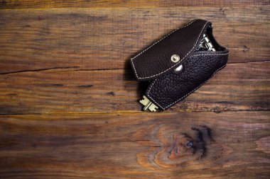 Deri anahtar çanta anahtar taşı üstünde tahta arka plan ile. Koyu arka plan. Anahtarlık. Çelik yelek şeklinde anahtar dava