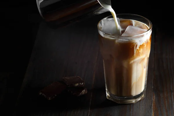 Iced coffee in a tall glass with cream poured over — Stock Photo, Image