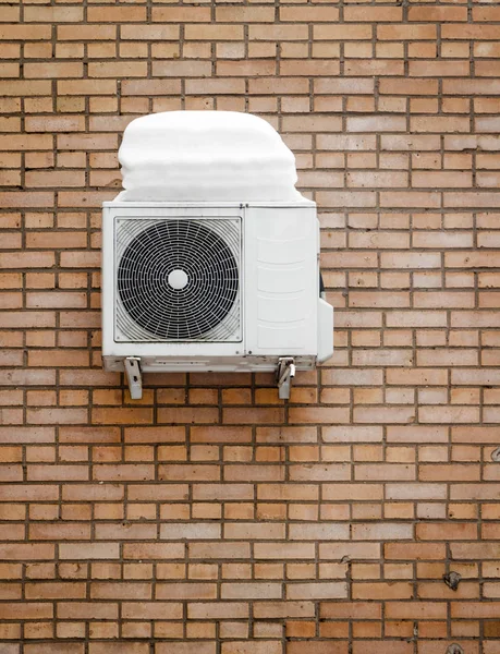 Air conditioner, installed on the wall of the house after winter snow.