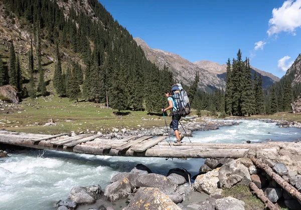 Hiker korsar floden vid bergen. — Stockfoto