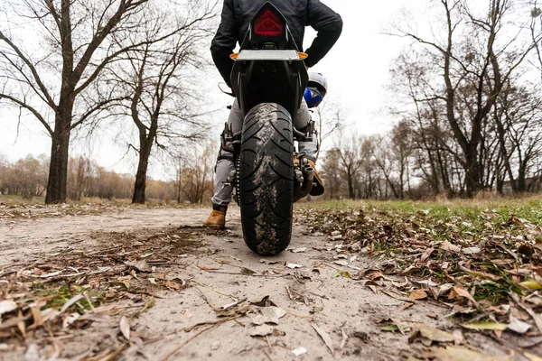 Rowerzysta siedzi na motocyklu, zbliżenie na tylne koło — Zdjęcie stockowe