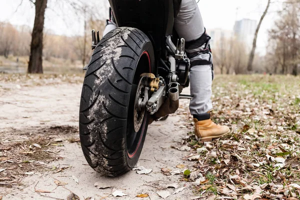 Biker sentado na motocicleta, close-up vista na roda traseira . — Fotografia de Stock