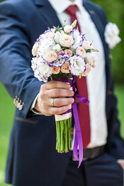 Groom holding wedding bouquet outdoors — Stock Photo, Image