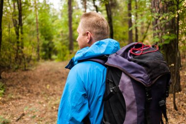 Uzun yürüyüşe çıkan kimse sırt çantası ile sonbahar ormanda yürüyor.